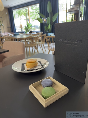 Two colorful macarons in blueberry and lime alongside a lemon and passion fruit pastry at Craig Alibone Pâtisserie