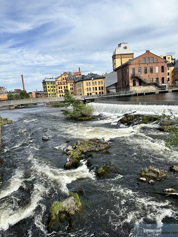 Pequeña cascada con edificios industriales de fondo